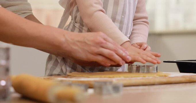 mother and little child cut out molds from dough in kitchen. close up