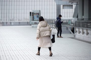 冬の都市の繁華街で歩く若い女性とビジネスマンの姿