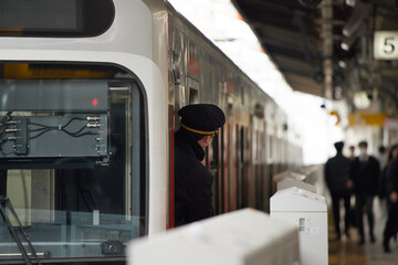 冬の朝の名古屋駅のホームで仕事する男性電車運転士の姿