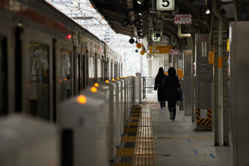 冬の駅のホームで電車待ちの人々の姿