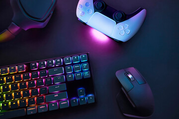 Top down view of various gaming accessories laying on table. Colorful illuminated devices.