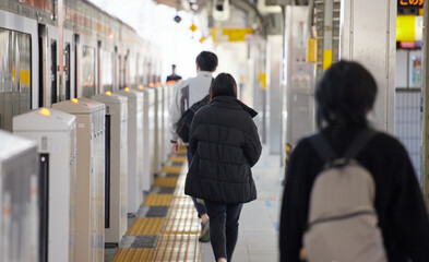 冬の朝の駅のホームで電車待ちの人々の姿