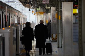 冬の朝の駅のホームで歩くシニア夫婦の姿