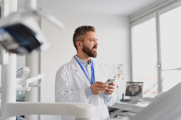 Portrait of handsome doctor in doctors office make phone call with patient.
