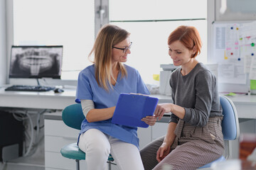 Patient talking with her female dentis during annual check up in dental clinic.