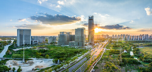 Fototapeta premium Aerial view of modern city skyline and road at sunset