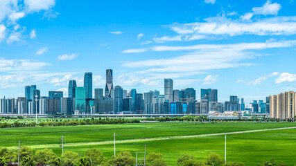 Obraz premium Modern cityscape with green field under blue sky at Hangzhou