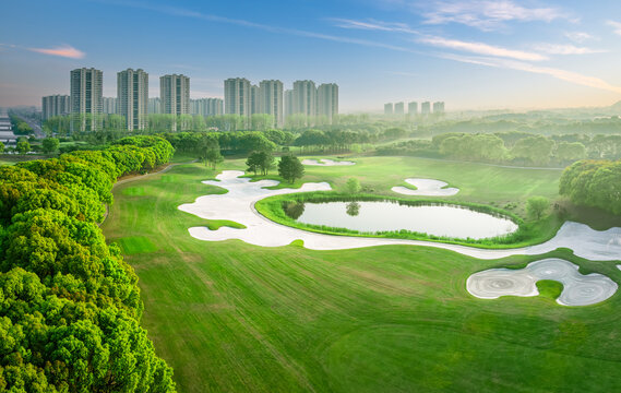 Scenic view of golf course with modern buildings in background