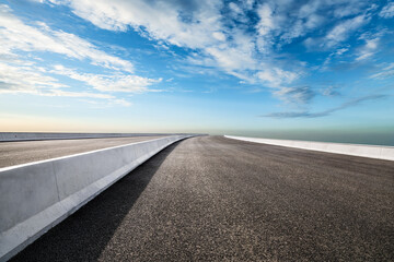 Empty asphalt road under blue sky with clouds