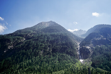 Naklejka premium Majestic Mountain Landscape with Forested Peaks and Clear Blue Sky..
