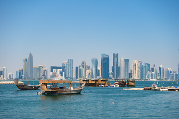 Naklejka premium Doha Skyline with Traditional Wooden Dhows on the Arabian Gulf – Urban and Maritime Contrast
