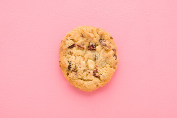 Dry cookie with chocolate and raisin pieces on light pink table background. Pastel color. Closeup. Sweet snack. Top down view.