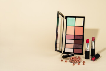Makeup products. Eyeshadow palette, lipsticks and brushes on pastel background. Copy space.