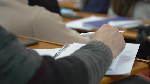 A student is taking notes in a lecture at the university close up