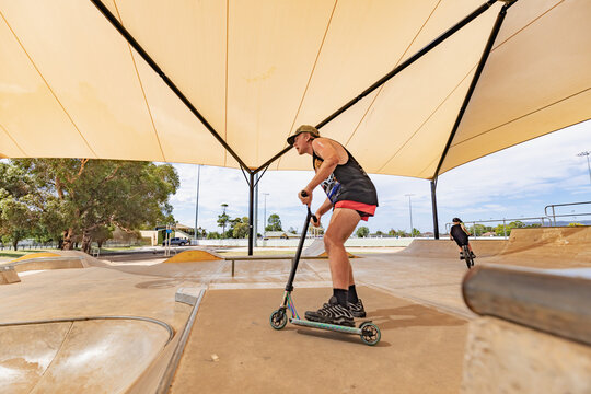 Teen boy riding scooter on ramps at skate park focus on background