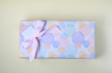 Colorful wrapped gift with a pink ribbon placed on a light surface for a special occasion