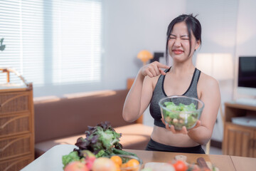 Young asian woman wearing sportswear pointing at a bowl of salad with a disgusted expression while...