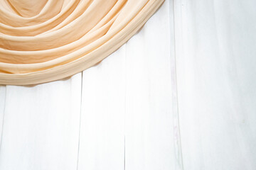 A beautifully draped peach-colored fabric with a soft flowing texture on a white background, ideal...