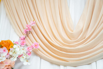 Elegant flower arrangement on white wooden background with fabric drape, romantic wedding backdrop