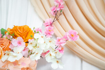 Elegant flower arrangement on white wooden background with fabric drape, romantic wedding backdrop