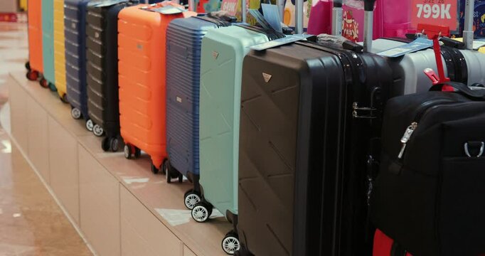 Colorful luggage collection lined up neatly, displaying diverse sizes and patterns of travel bags waiting in retail display area for potential travelers