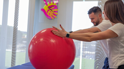 Physiotherapist helps a young woman perform shoulder stretching exercises for rehabilitation