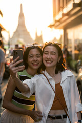 Fototapeta premium Two happy tourists taking selfie in bangkok with wat arun in background