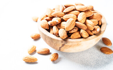 Almond nuts in wooden bowl at white background. Close up.