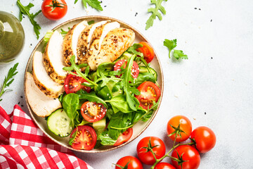 Chicken salad with grilled meat and vegetables at white table. Top view with copy space.