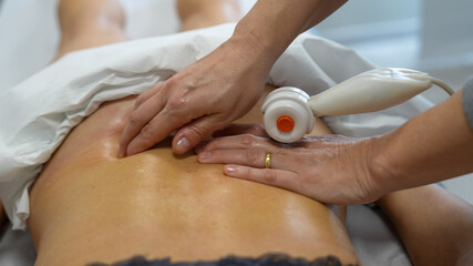 Physiotherapist performs shoulder massage with TECAR therapy on a woman for pain relief