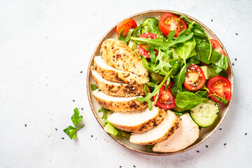 Chicken salad with grilled meat and vegetables at black table. Top view with copy space.