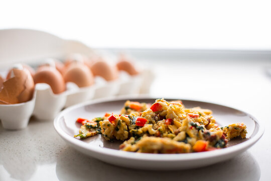 plated scrambled eggs with veggies next to an egg carton