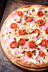 Pizza with ham, cherry tomatoes and mozzarella cheese. Wooden background. Soft focus. Close up.