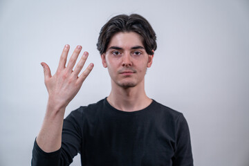 Fototapeta premium Portrait of a young man showing his right hand with open fingers isolated on white background.