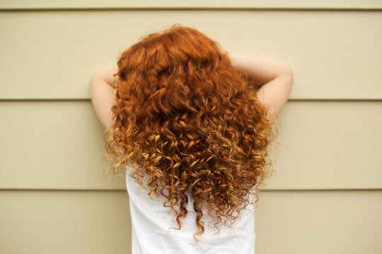 Redhead girl leaning on a wall