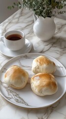 Golden Buns on Marble Plate with Tea and Eucalyptus Arrangement Capturing Culinary Still Life and Warm Tones for Stock Photo Platform