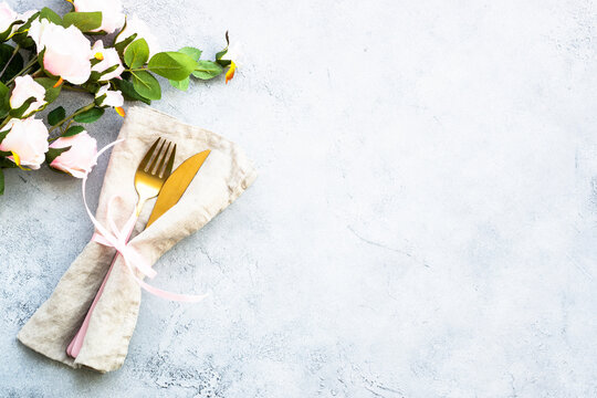 Table setting, luxury tavle decoration with modern cutlery and pink flowers. Top view at white background with copy space.