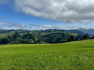 Obraz premium Scenic view of lush green hills under a partly cloudy sky.