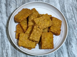 Crispy flour fried tempeh, served on a white plate.