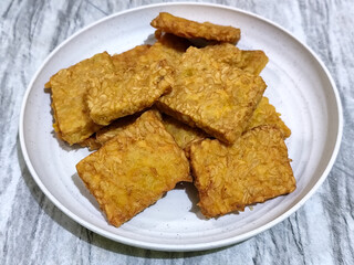 Crispy flour fried tempeh, served on a white plate.