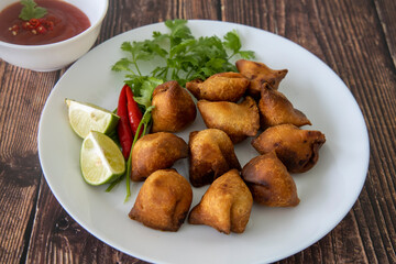 Indian fried Samosa filled with spiced potato, served with lime wedges and sauce