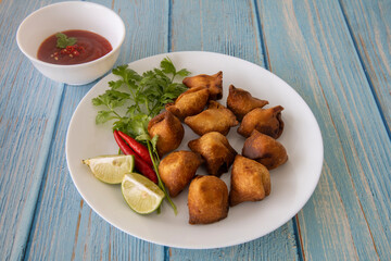 Indian fried Samosa filled with spiced potato, served with lime wedges and sauce