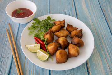 Indian fried Samosa filled with spiced potato, served with lime wedges and sauce