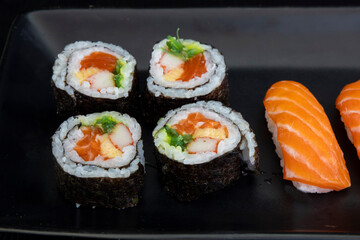 Japanese salmon maki rolls and salmon nigiri on black plate