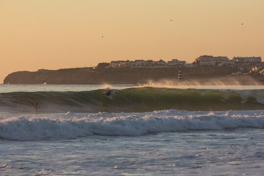 Surfers in the water with the warm colors of the sunset - Powered by Adobe
