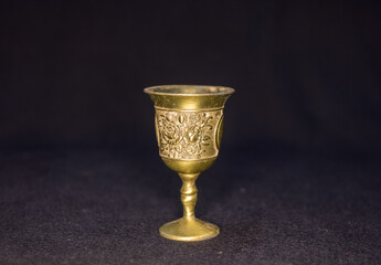 Antique floral engraved metallic wineglass or goblet isolated in black background 