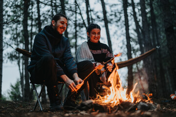 A cozy moment shared between two people at a forest campsite, warming up by a flickering bonfire...