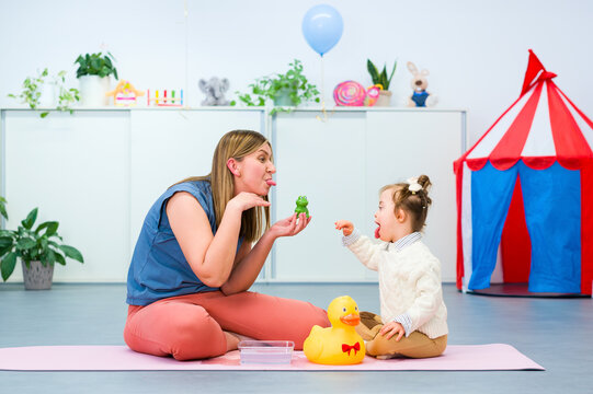 Nonverbal child with Down syndrome learning baby sign language with the help of a speech therapist. Child therapy, neurodiversity, learning difficulty, developmental disability.