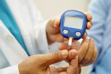 Asian doctor using digital glucose meter for check sample blood sugar level to treatment diabetes.