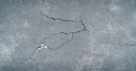 Obraz premium A close-up view of cracked concrete surface, showcasing various fissures and texture, emphasizing wear and potential weathering.